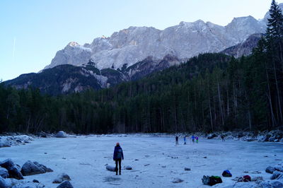 People on ice rink in forest against mountains