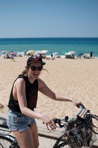 Woman with bicycle at beach against sky