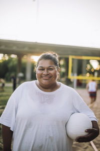 Portrait of smiling oversize woman wearing white t-shirt and holding volleyball