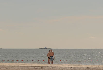 Rear view of man looking at sea against sky