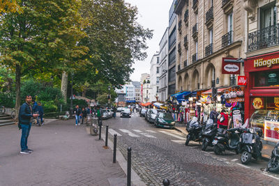 People on road by trees in city