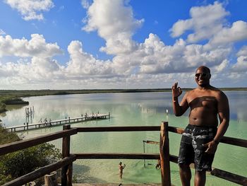 Portrait of shirtless man standing against sea