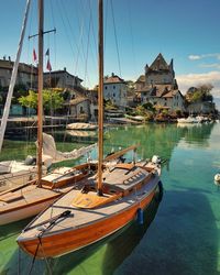 Boats moored at harbor by buildings against sky