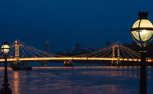 Illuminated suspension bridge over river at night