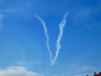 Low angle view of vapor trail against blue sky