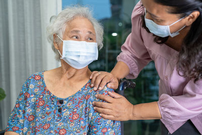 Caregiver help asian senior woman sitting on wheelchair and wearing a face mask  