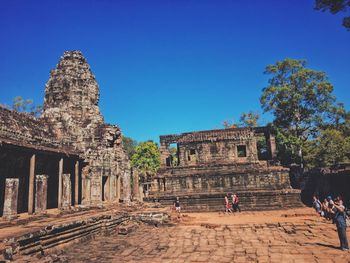 Tourists at temple against clear sky