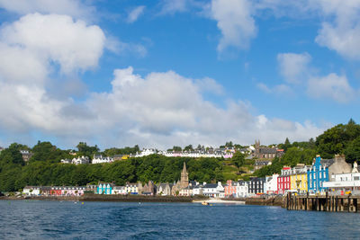 Scenic view of sea by buildings against sky