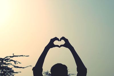Silhouette man with heart shape against sky during sunset
