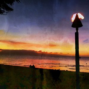 Silhouette beach against sky during sunset