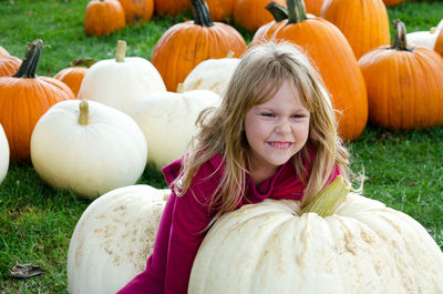 Child trying to lift a white pumpkin at a fall pumpkin patch