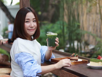 Smiling woman drinking a matcha green tea latte in the morning at a cafe  