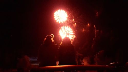 Rear view of silhouette woman with fire crackers at night