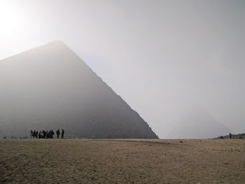 People standing on desert against pyramid