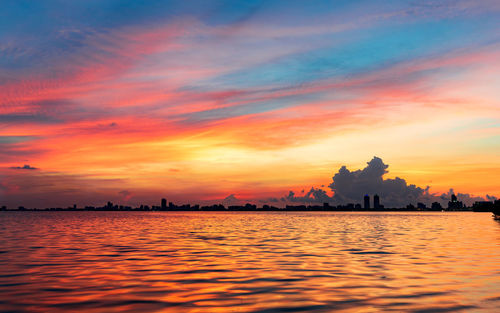 Scenic view of sea against dramatic sky during sunset