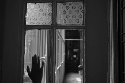 Cropped hand touching window at home