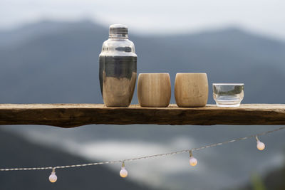 Selective focus stainless steel thermal water bottle and bamboo coffee mug placed on a wooden 