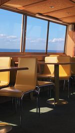 Empty chairs and tables in restaurant against sky