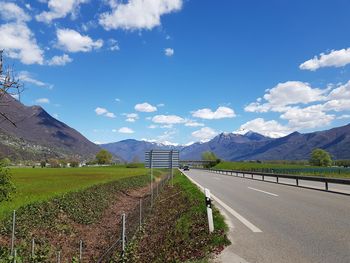 Road by field against sky