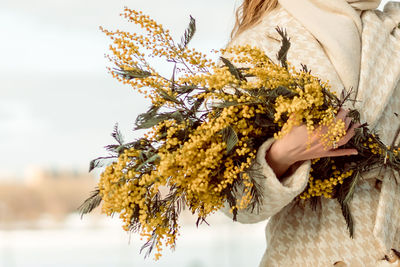 A woman with a bouquet of acacia flowers.the concept of the holiday - march 8, easter, women's day