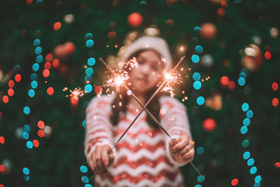 Portrait of young woman with illuminated string lights at night