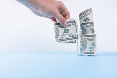 Close-up of hand holding paper over white background