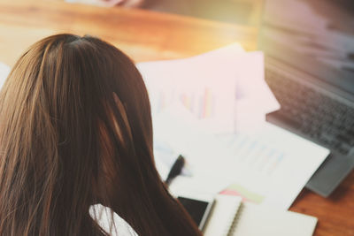 Rear view of businesswoman working at table in office