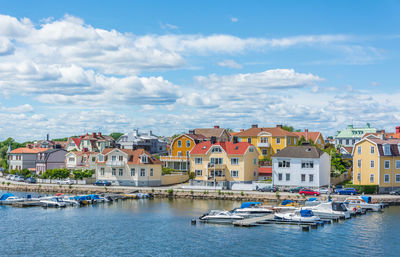 Sailboats in sea by town against sky