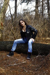 Portrait of young woman sitting on sidewalk in forest