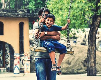 Portrait of a smiling young man holding woman standing against trees