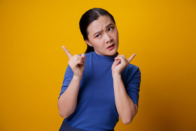 Portrait of man smoking cigarette against yellow background