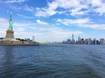 Statue of liberty amidst river against cloudy sky