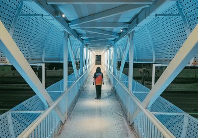 Rear view of woman walking on footbridge