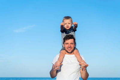 View of father and son on beach against sky