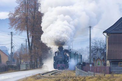 Rear view of man standing on railroad track against sky