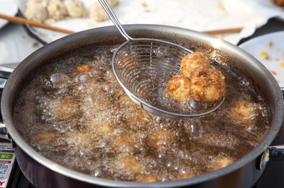 High angle view of strainer with fried food over boiling oil in container on stove