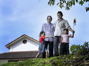 Low angle view of family standing against sky