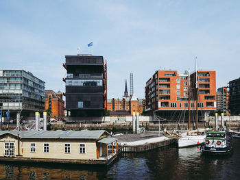 Buildings by river against sky in city