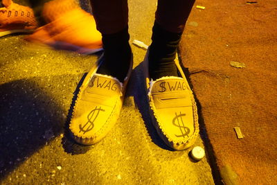 Low section of person with text wearing shoes while standing on street