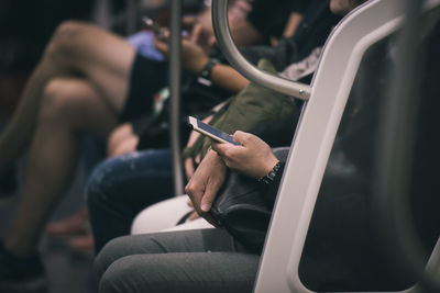 Rear view of man using mobile phone while sitting on seat
