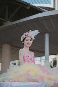 Smiling girl standing against built structure