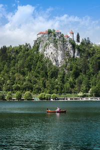 People sailing in boat at lake against mountain