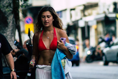 Portrait of young woman standing on street in city