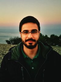 Portrait of man wearing sunglasses at beach against sky