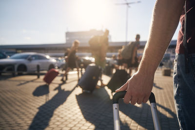 Group of people walking to airport terminal at sunset. selective focus on hand of man with suitcase.