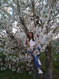 Full length of woman on cherry blossom tree in park