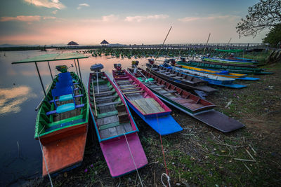 Multi colored boats moored on beach against sky during sunset
