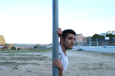 Digital composite image young man looking away while standing on field against clear sky during sunset