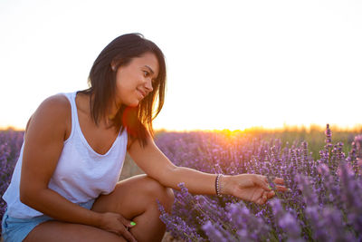 Young latin woman picks lavender flowers at sunset. handcrafted production with aromatic plants