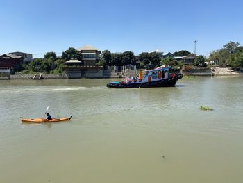 People on boat in river against clear sky
